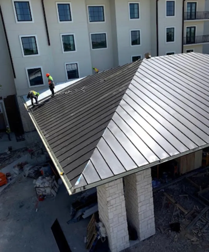 Crew installing standing seam metal roof panels on a commercial project in Dayton